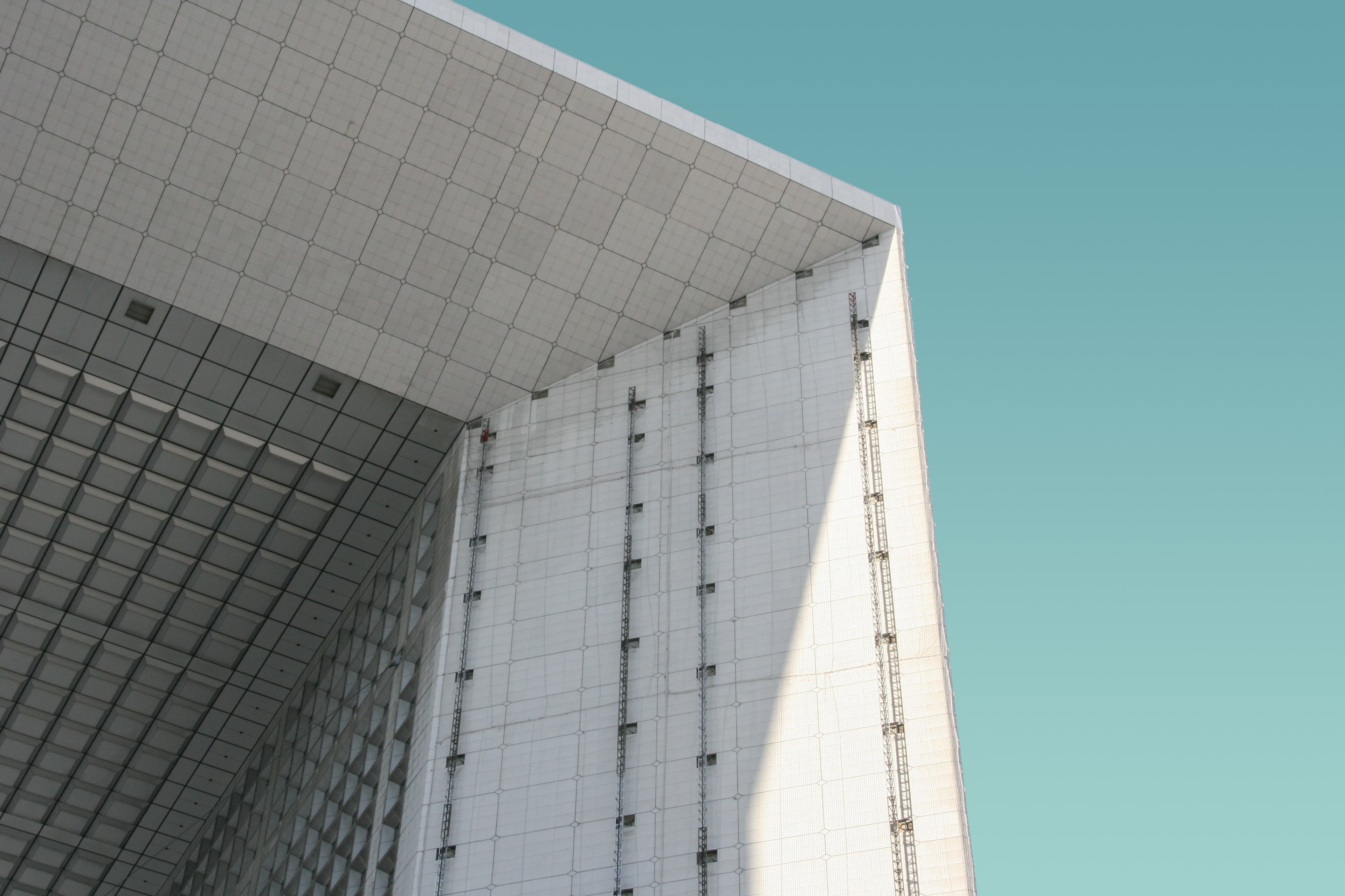 Low-angle view of a modern building with undulating curved balconies and glass railings against a twilight sky.