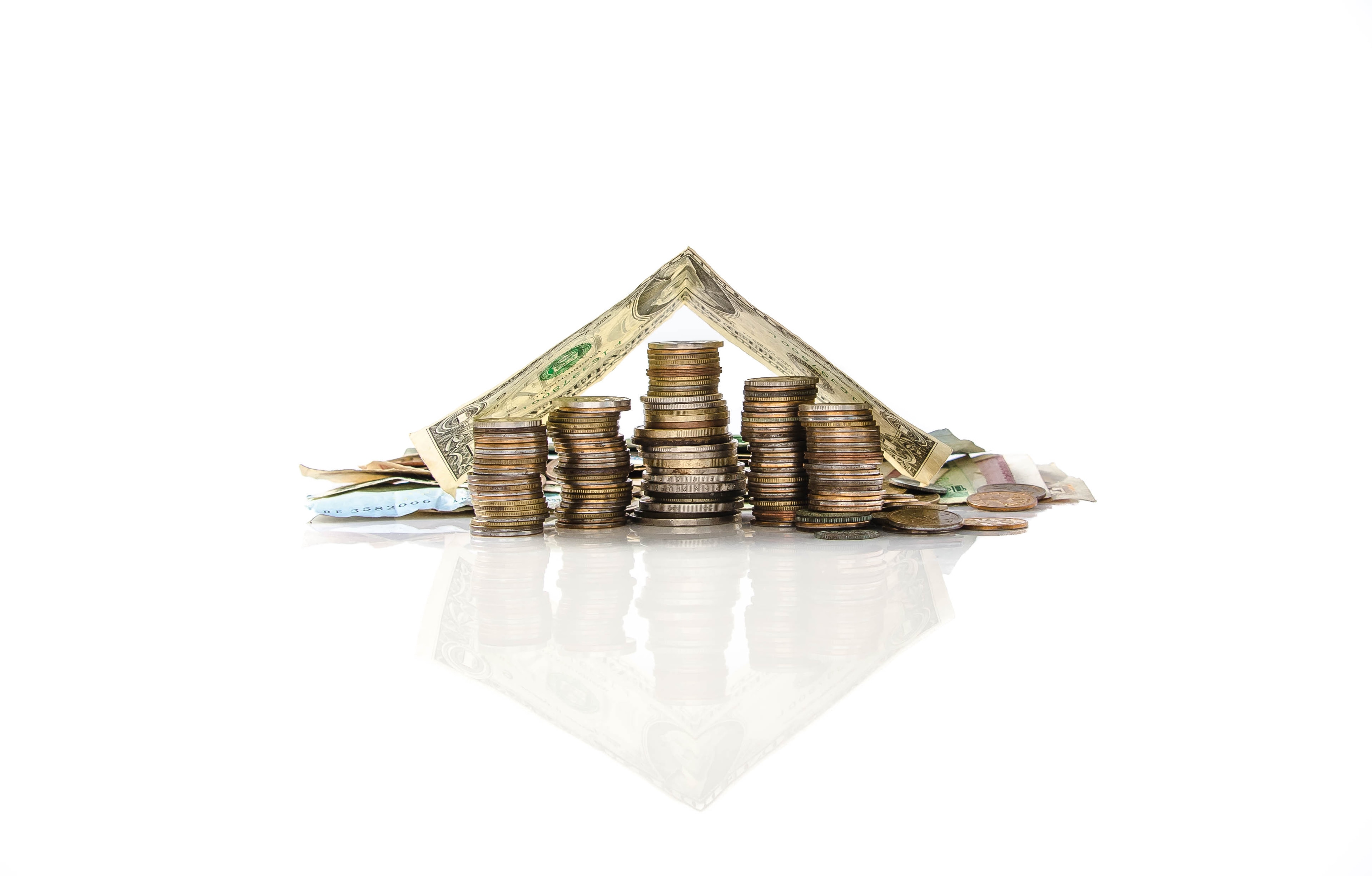 Stacked coins under a dollar bill shaped like a house roof